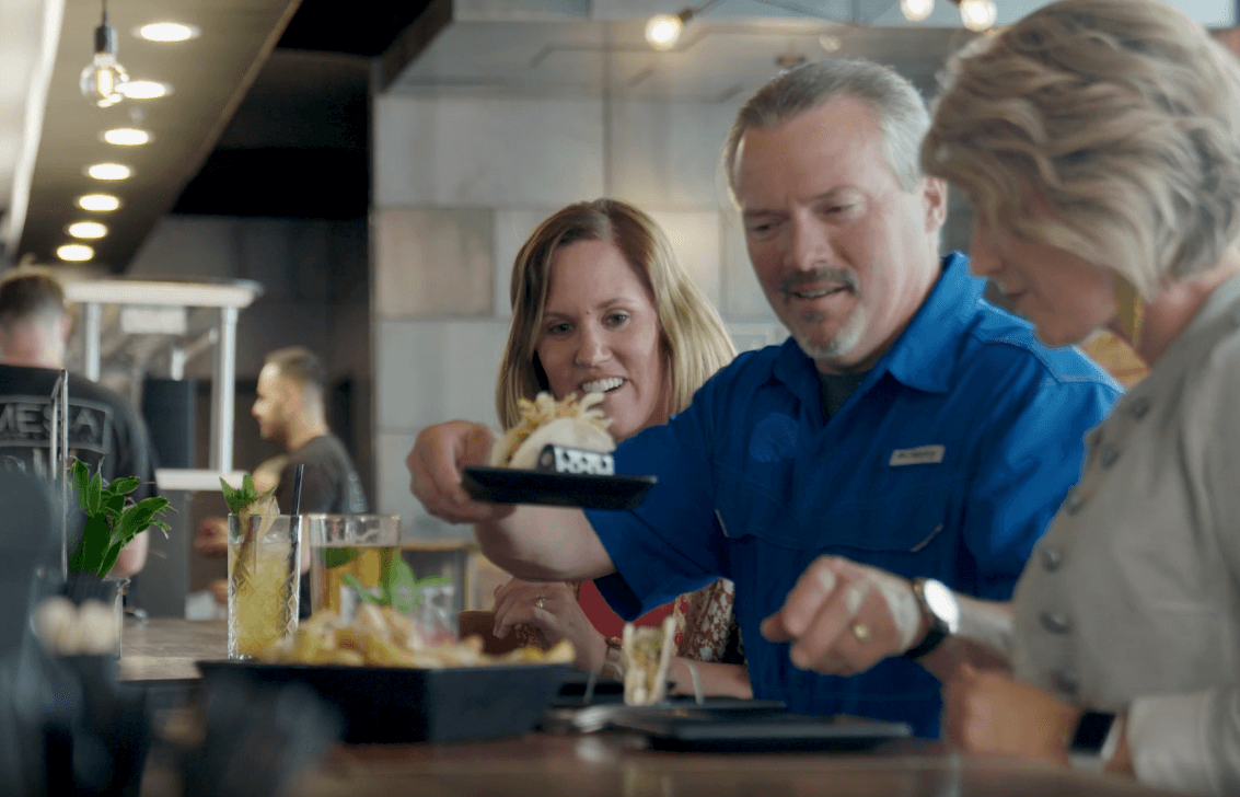 Three people enjoy food and drinks in Nampa.