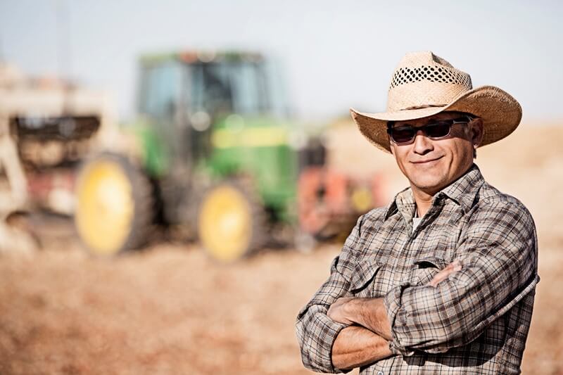 A farmer proudly poses for a photo in front of a tractor in Nampa.