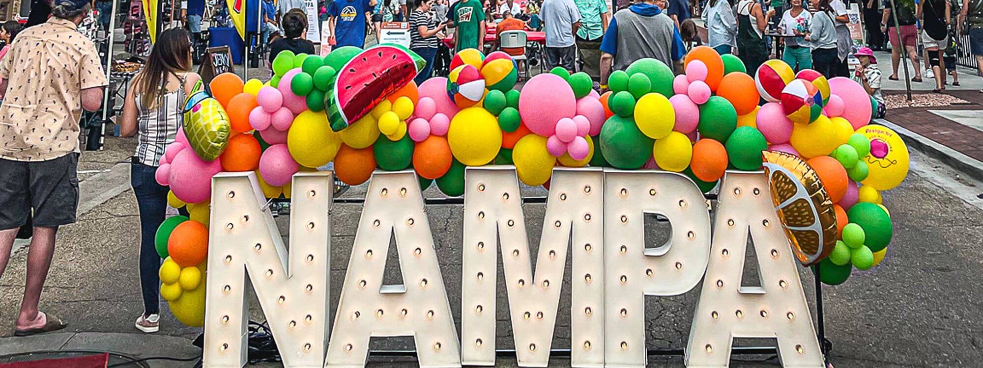 Actividades gratuitas A large sign spelling Nampa with colorful balloons behind.