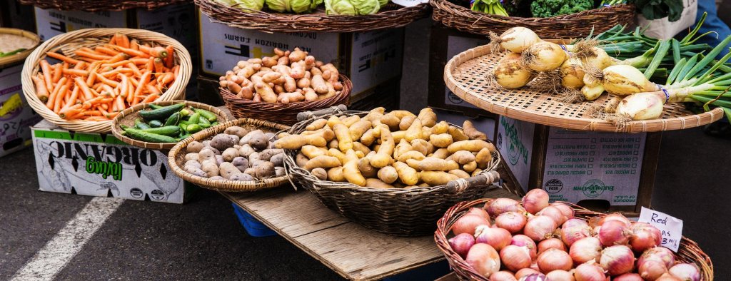Mercados agrícolas A farmer's market with various vegetables like carrots, potatoes, green onion, and shallots on sale in Nampa, ID.